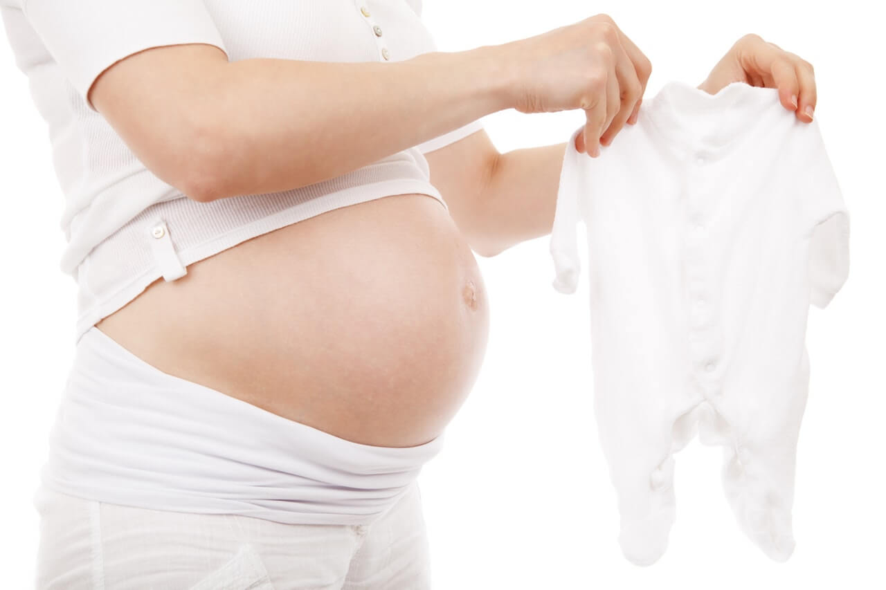 pregnant woman holding babygrow